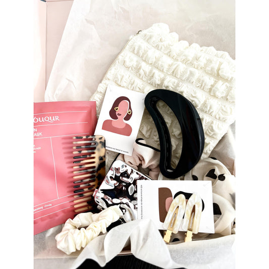  beauty gitf pack including a pink mask, comb, and hair accessories on a white surface.